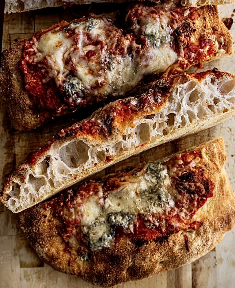 Cross-section of a Roman pizza slab showing an open, airy crumb and a crisp golden base